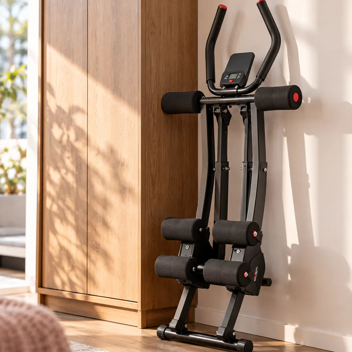 Ab Trainer noir replié, rangé debout contre un mur à côté d’une armoire